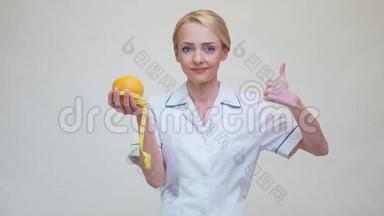 <strong>营养学家</strong>医生健康的生活方式理念-拿着橘子水果和量胶带